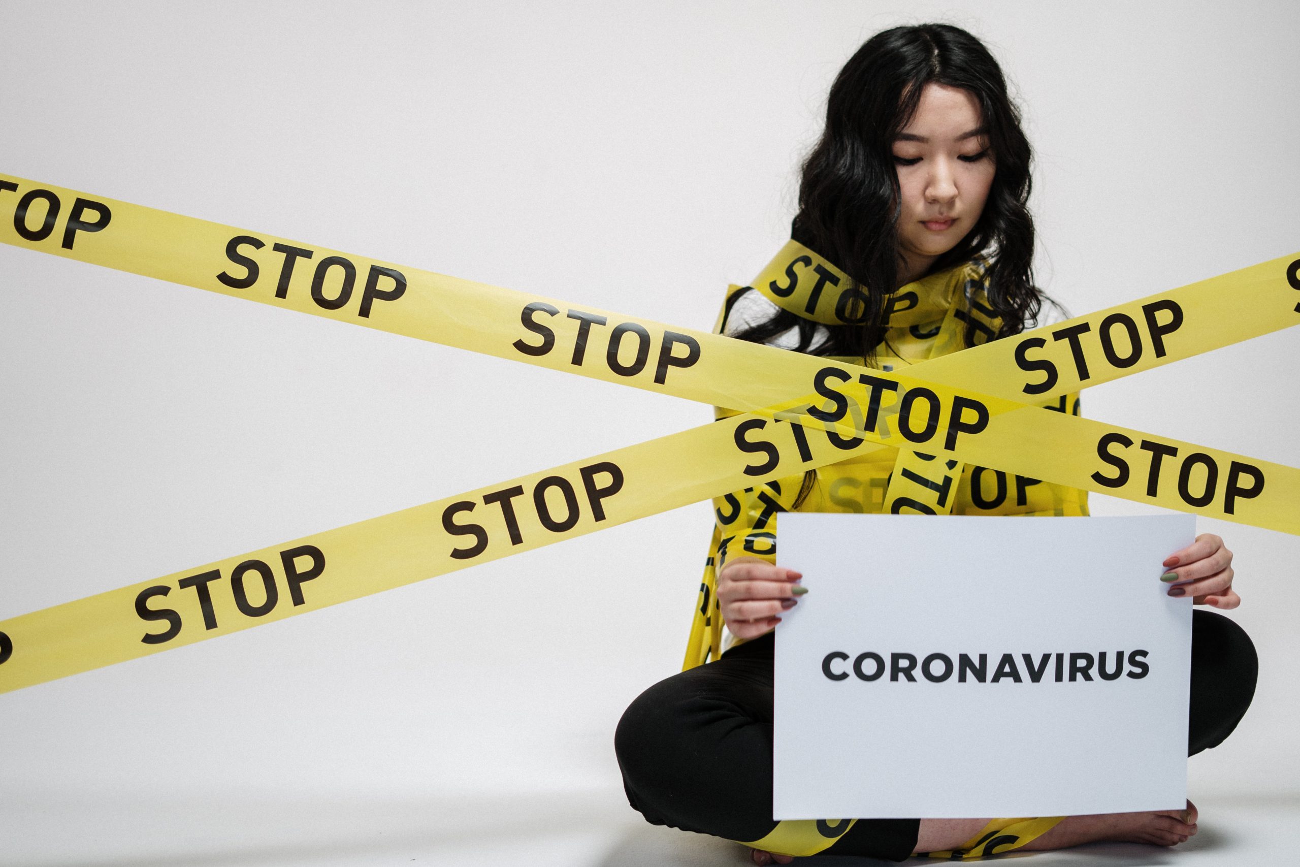 Woman sitting bonded by stop sign about coronavirus